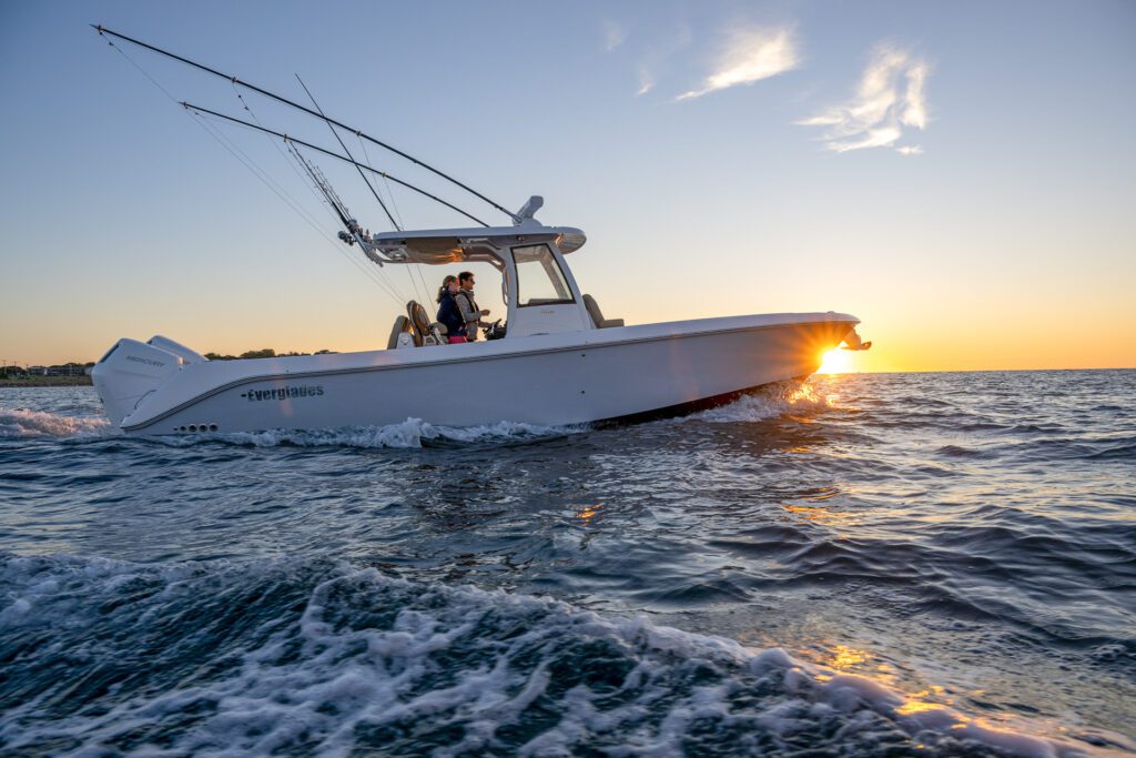 1272 Two people navigating the Unsinkable Everglade boat on the ocean during a vibrant sunset