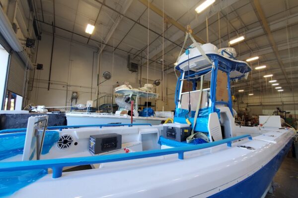 Blue and white Everglade boats being built in an indoor workshop