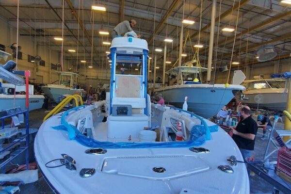 An Everglades boat being built in an indoor facility with workers and equipment around