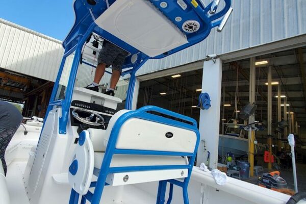 A person standing on a blue and white Everglades boat inside a workshop