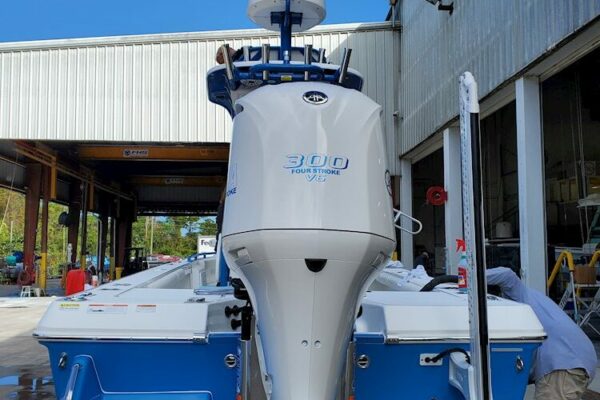 A white 300 horsepower four-stroke outboard motor mounted on the stern of a blue Everglades boat