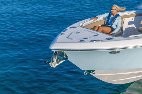 A person sitting on the bow of an Everglades boat on blue water