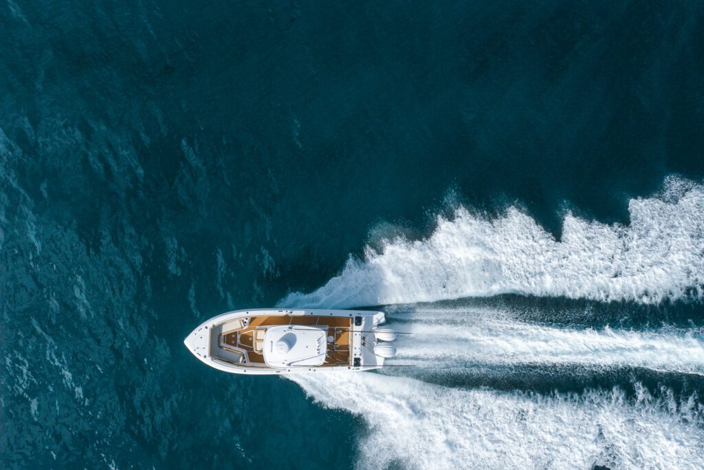 Aerial view of a white Everglades boat cruising on blue water, creating a wake