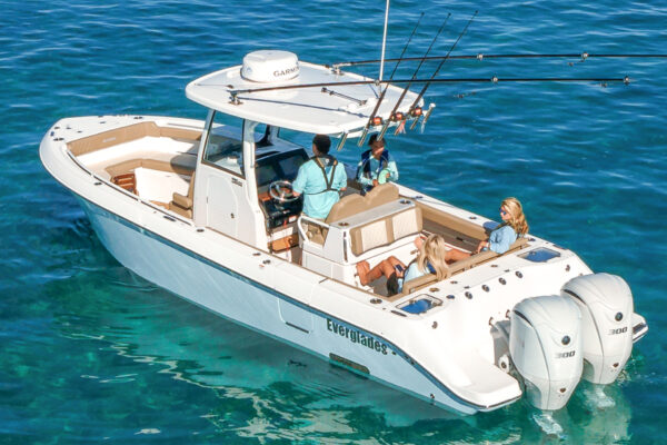 People on a white Everglades fishing boat with twin outboard engines on clear blue water