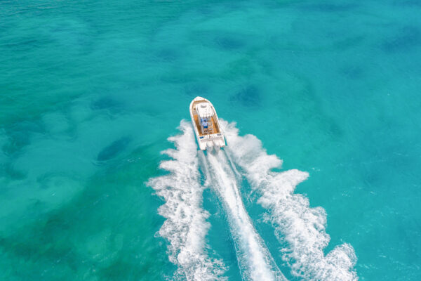 Aerial view of an Everglades boat speeding on turquoise water creating white wake trails