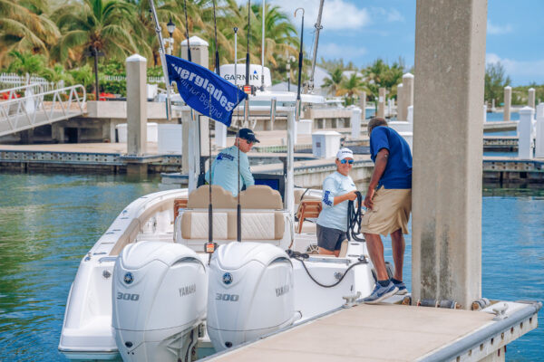 A boat docked at a pier with two people standing beside it, holding a rope