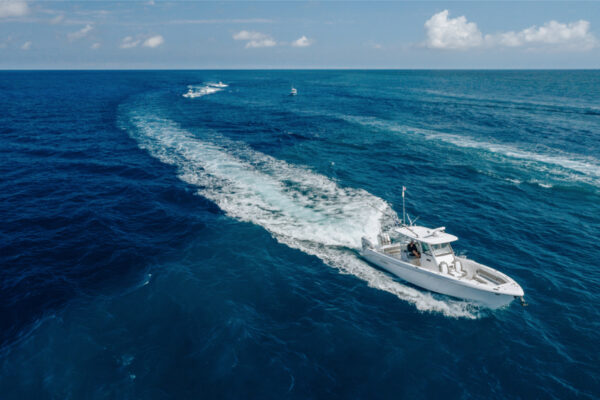 DJI_0562_4695 Aerial view of an Everglades boat leaving a large wake as it speeds through the open ocean with other boats visible in the distance under a partly cloudy sky