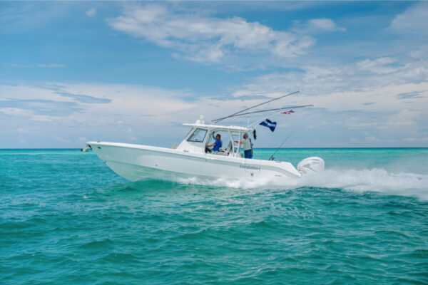 JJS00005_6382 An Everglades boat speeding across turquoise water with fishing rods and flags visible and a partly cloudy sky in the background