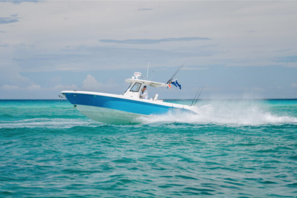 JJS00070_8312 A blue and white Everglades boat speeding across turquoise water with a cloudy sky in the background