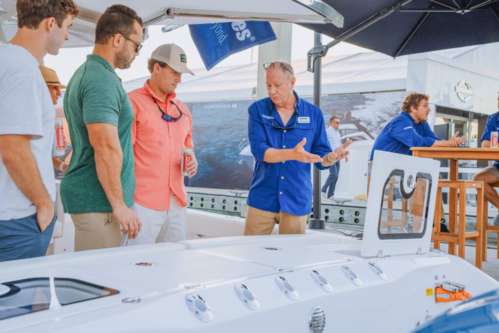 JJS02653 A man demonstrating the features of a boat to a group of attentive guys, highlighting its key elements