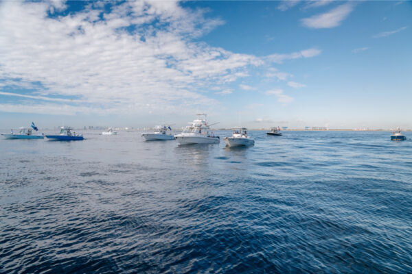 JJS06724_2651 A fleet of Everglades boats on calm blue water under a sky dotted with clouds
