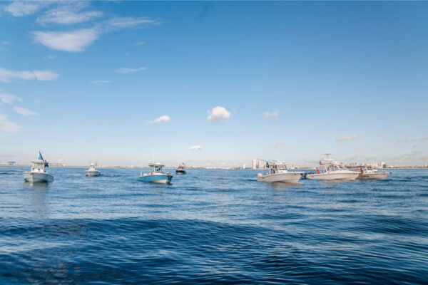 JJS06737_3092 Several boats floating on calm blue water under a clear sky, with a distant shoreline visible in the background