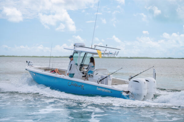 JJS06857_1461 An Everglades boat cruising through the water with two people on board and fishing rods visible under a partly cloudy sky