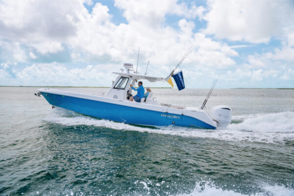 JJS06864_253 An Everglades boat speeding across the water with two people on board and fishing rods visible under a partly cloudy sky