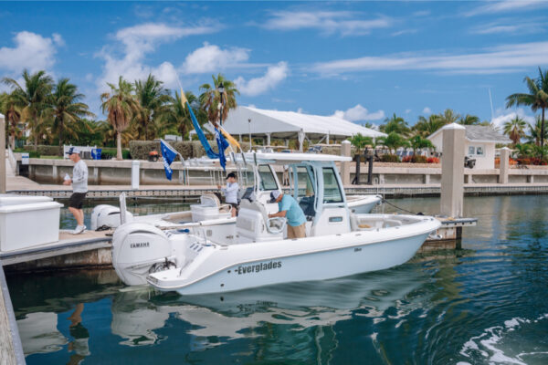 JJS06900_5948 An Everglades boat docked at a marina with people on board preparing for a trip under a sunny sky with palm trees and other boats in the background