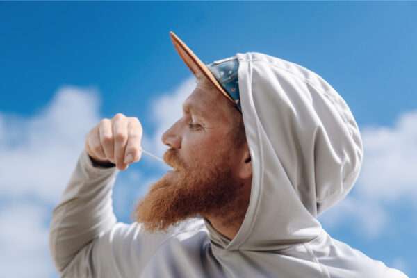 JJS07250_4535 Man in a hoodie and cap against a blue sky.
