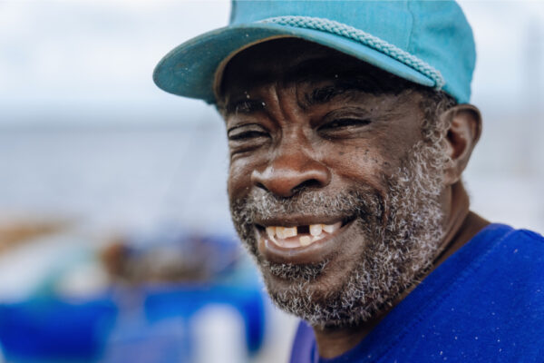 JJS07332_2028 A close up of a smiling man wearing a blue hat with a blurred background of blue and white tones
