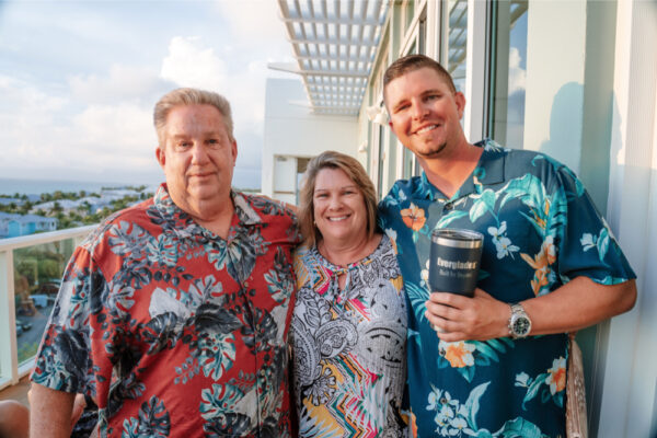 JJS07402_8463 Two men and one woman in floral shirts with scenic view from a balcony