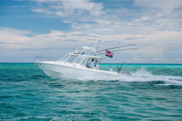 JJS09707_4735 Everglades fishing boat cruising on turquoise water under a cloudy sky, American flag waving