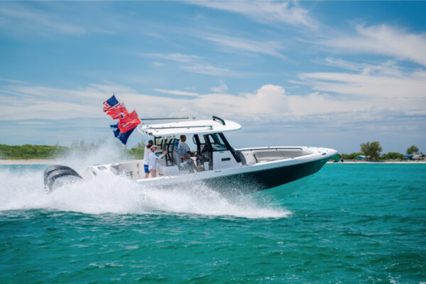 JJS09752_9695 An Everglades boat speeding across turquoise water with flags flying at the back and a bright, partly cloudy sky in the background
