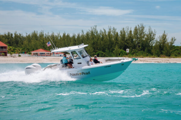 JJS09766_2919 An Everglades boat speeding across turquoise water with passengers on board and a shoreline with trees and buildings in the background