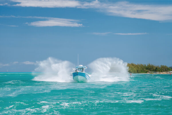 JJS09819_3072 An Everglades boat creating a large splash with a shoreline and trees visible in the background under a partly cloudy sky