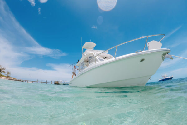 UW8102_6958 A white boat floating on clear turquoise water with a bright blue sky in the background