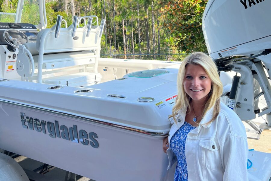 A woman standing beside an Everglades boat with Yamaha outboard engine, trees in the background
