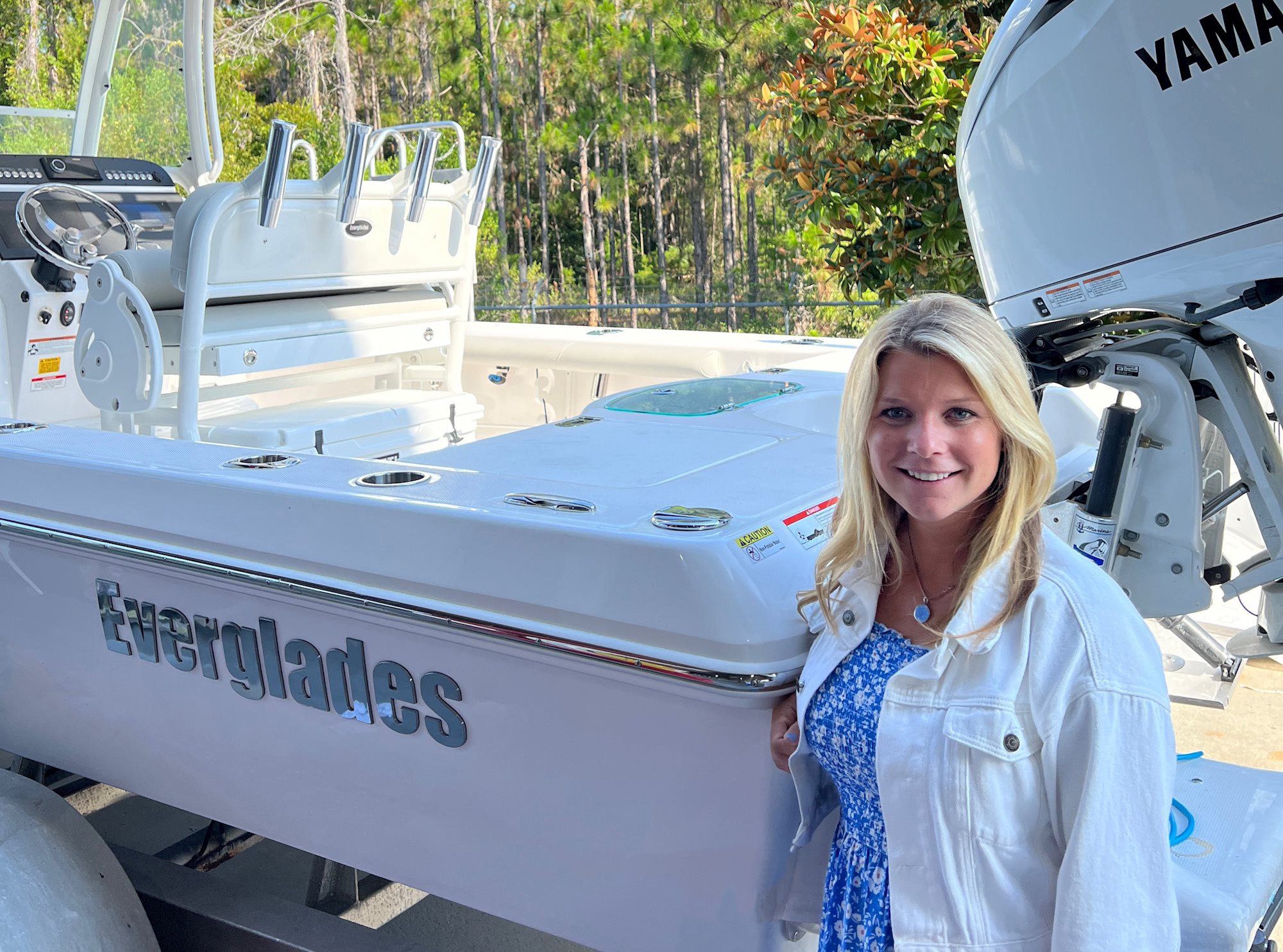 A woman standing beside an Everglades boat with Yamaha outboard engine, trees in the background